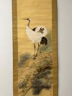 A pair of cranes standing on pine tree - Riho