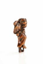 Un netsuke en buis représentant un sennin marchant avec un