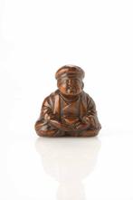 Een boxwood netsuke die een kind afbeeldt dat in de