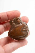 Un netsuke en buis représentant un singe sur une pêcher. -