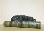 Presse-papier en forme de chien endormi sur un livre -