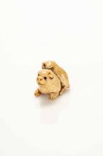 Een fijne en zachte hertenantler netsuke waarop twee puppys