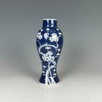 Vaas met pruimenbloesem op indigo-ondergrond met witruimte