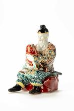 An inusual kutani porcellain okimono of a man with child -
